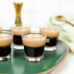 a jigger, spoon and glass shot glasses with baby guinness