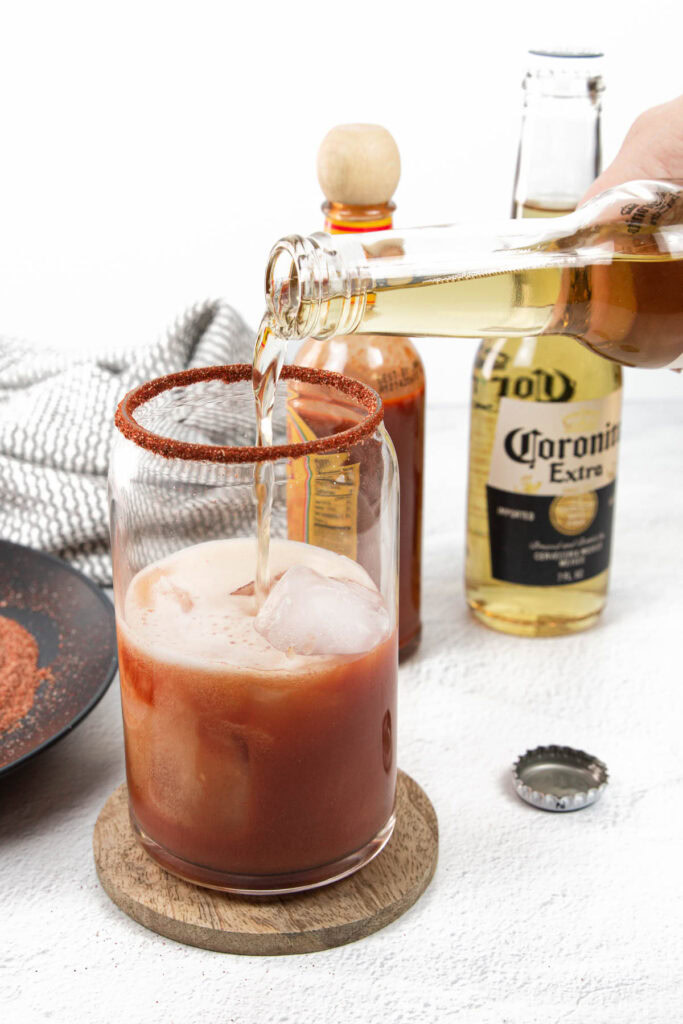 a corona pouring into a michelada cocktail