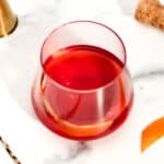 A glass with a red negroni in it.