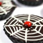 No-Bake Mini Chocolate Ganache Tarts, elegantly finished with a white icing spider web design and topped with a playful red candy spider.