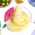 a top-down view of a boozy dole whip with a pink cocktail umbrella