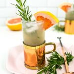 grapefruit mule cocktail on a pink hexagon plate with a copper spoon and rosemary