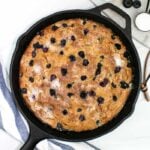 a pint of blueberries with a cast iron skillet with blueberry coffeecake