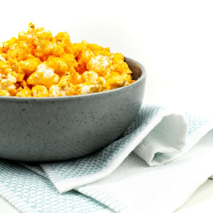 cheddar cheese popcorn in a gray bowl with a blue tea towel