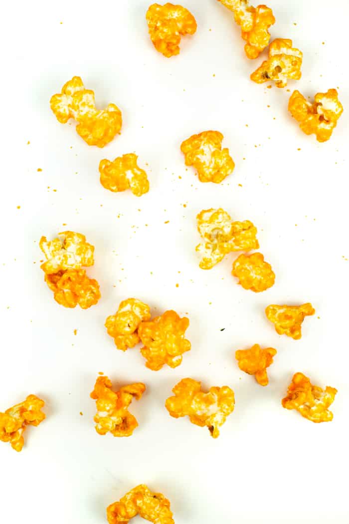 kernels of cheddar cheese popcorn on a white surface