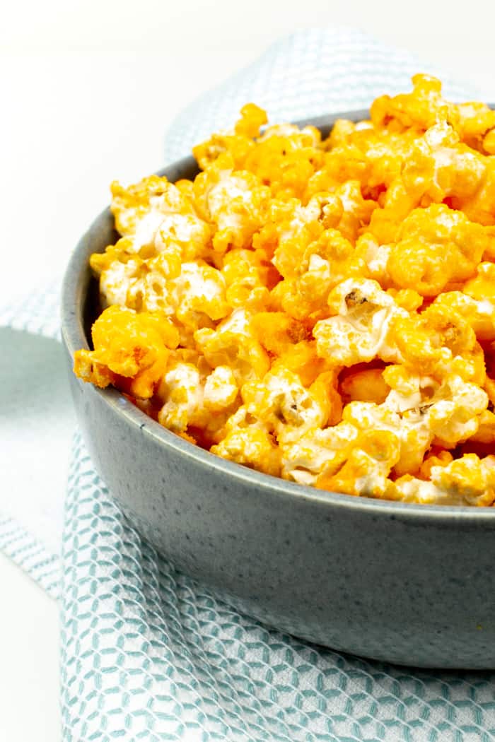 a heaping serving of cheese popcorn in a grey bowl