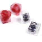 ice cubes with berries frozen in them lying on a white surface