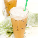 two iced irish coffee cocktails on a white background with a green tea towel