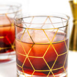 two Cheerwine Old-Fashioned with a gold jigger on a white background