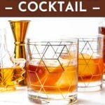 Two glasses of maple old-fashioned cocktail sit on a white surface, accompanied by a gold jigger and a glass syrup dispenser in the background. Text highlights this maple old-fashioned cocktail recipe.