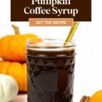 A jar of dark pumpkin spice syrup with a gold spoon, surrounded by pumpkins and cinnamon sticks, with text promoting the recipe.
