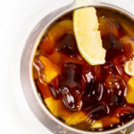 a top view of whiskey and coke gummies with a lime wedge in a cocktail glass on a white background