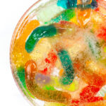 closeup of vodka gummy worms in a glass topped with sprite