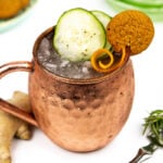 a gingerbread mule in a copper mug on a white background with a silver absinthe spoon