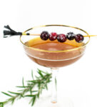 a christmas sugar plum sidecar with fresh rosemary on a white background