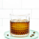 a coffee old-fashioned on a blue plate with coffee beans