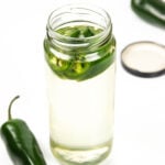 jalapeño peppers with an open jar of spicy syrup