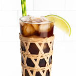 a cuba libra in a vintage cocktail glass with a rattan casing