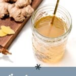A glass jar of ginger syrup with a decorative spoon, beside fresh ginger root on a wooden board. Text reads: "Homemade ginger syrup for cocktails & mocktails.