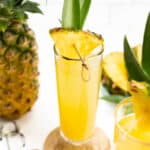 a pineapple mimosa on a white background with a whole pineapple