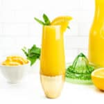 a virgin mimosa with a garnish of mint and an orange slice