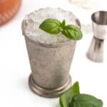 Julep cup in focus with mason jar, metal jigger and terra cot in background