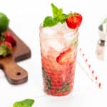 a cutting board with limes and strawberries with a berry cocktail