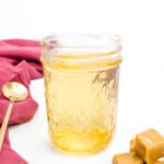 a jar of caramel vodka with a stack of caramel candy.