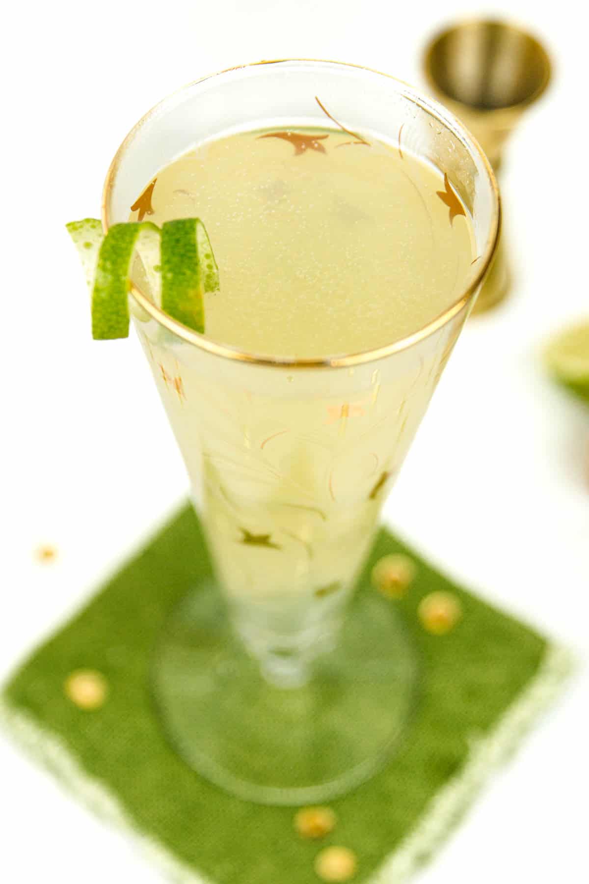 A lime spiral garnishes the gold rim of a glass containing a Champagne Moscow Mule.