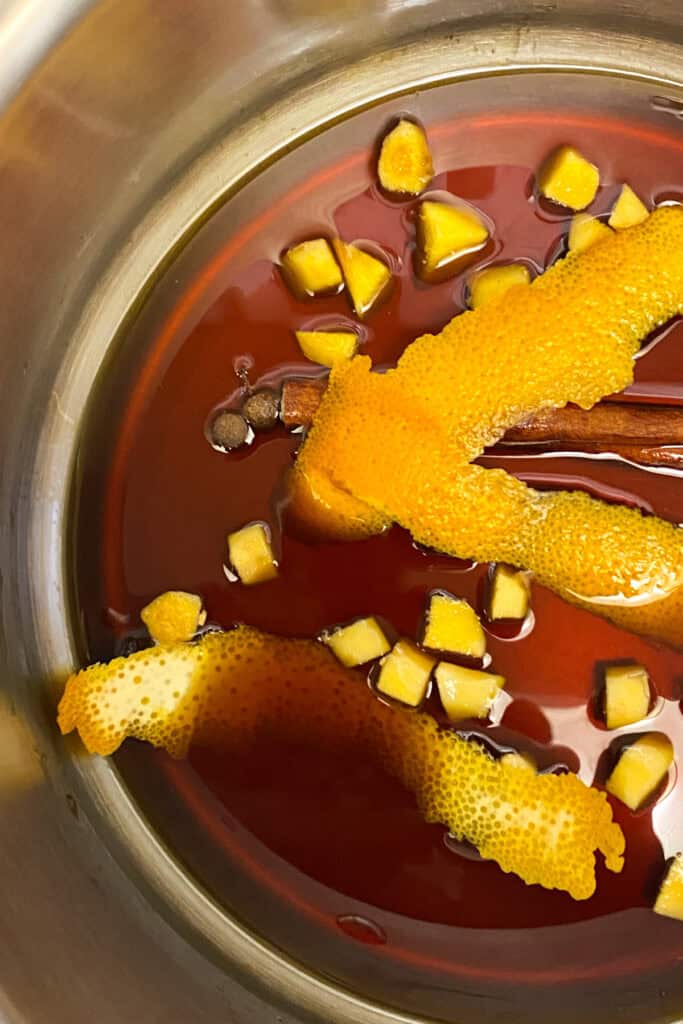 An old-fashioned pot of liquid with orange peels and cinnamon sticks, perfect for a Christmas celebration.
