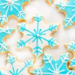 Festive blue and white sugar cookies shaped like snowflakes on a white background