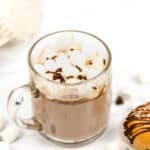 A mug of salted caramel hot chocolate garnished with marshmallows and chocolate sprinkles.