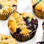 Berry muffins sit on a white surface.