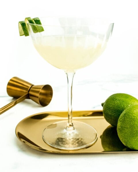 a classic lime daiquiri in a coupe glass on a gold serving tray.