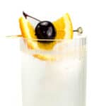 An orange and cherry garnish on a bubbly clear cocktail.