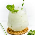 A Frozen Mojito with a mint sprig and striped green and white straw.