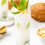 A coconut mojito with lime and mint leaves in a glass.