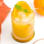 A glass of orange juice with a mint sprig.