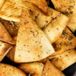 A plate of pita chips with sesame seeds on it.