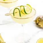 Two martini glasses with lime slices and a martini shaker.