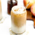 Two mugs of Apple Crisp Macchiato with whipped cream and apples.