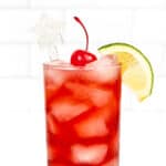 A red drink with a lime and star garnish.