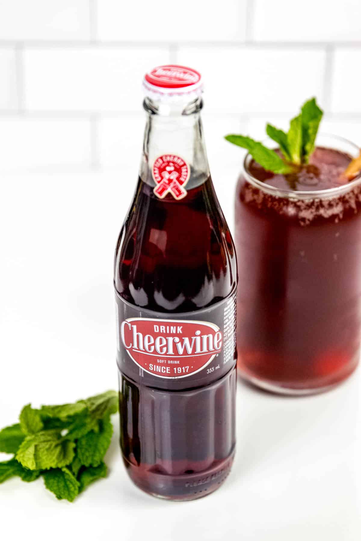 A bottle of iced tea with mint leaves next to it.