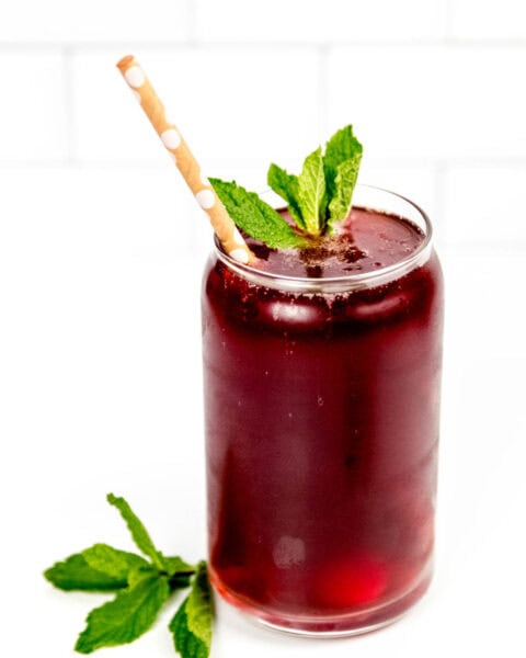 A drink with a straw and mint leaves.