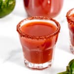 Two glasses of spicy Sangrita with jalapeños and limes.