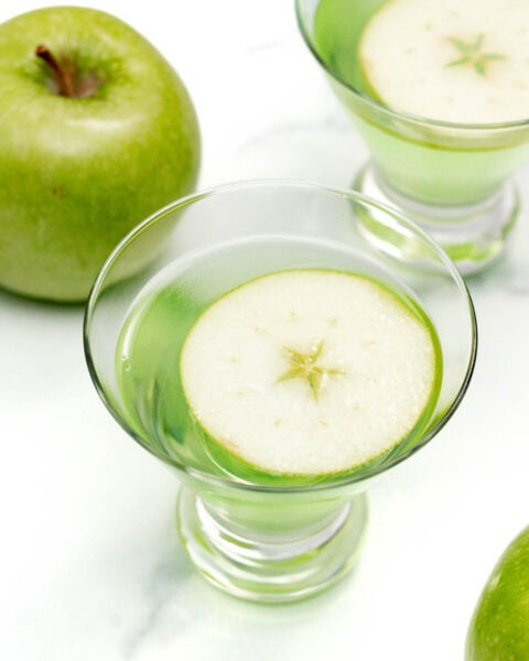 An Appletini, a glass of green liquid with a slice of apple in it.
