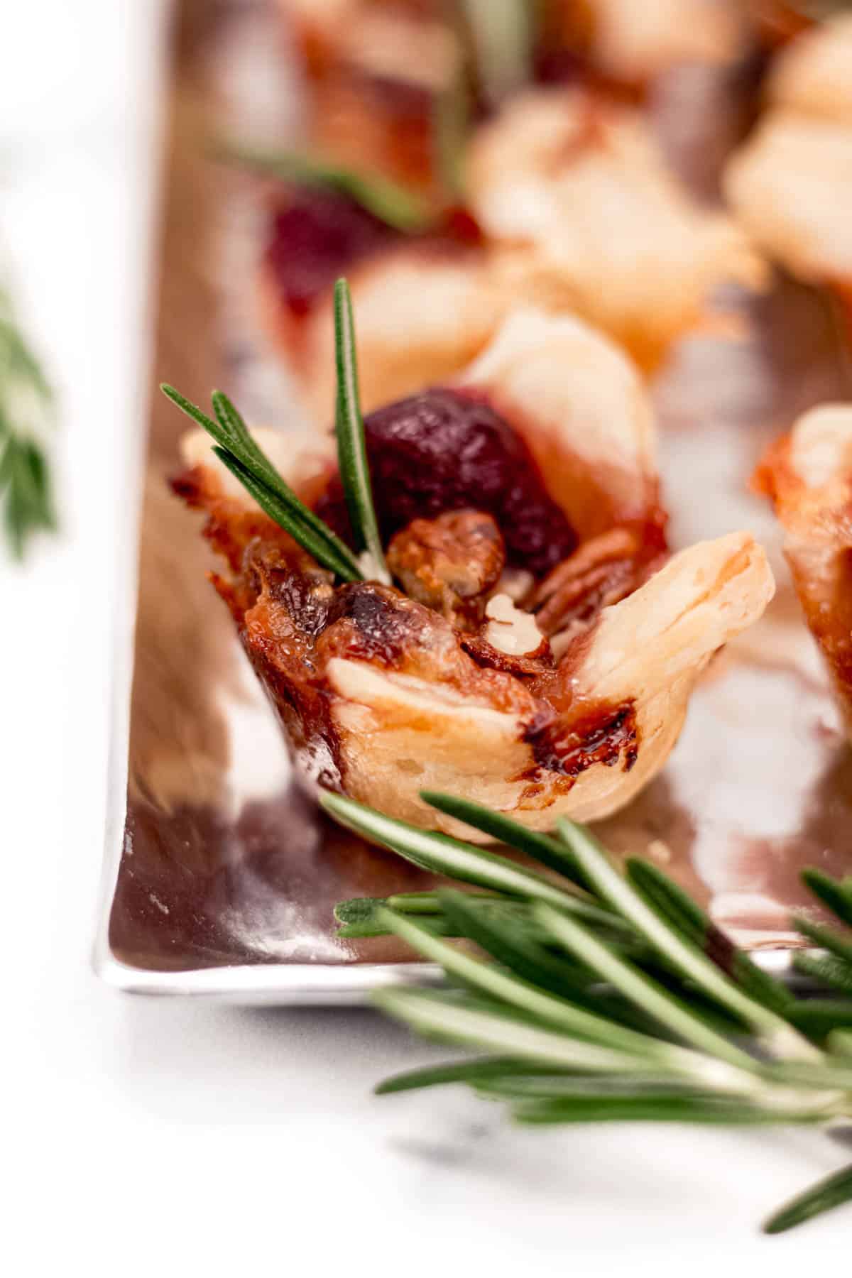 Cranberry tartlets on a tray with rosemary sprigs.