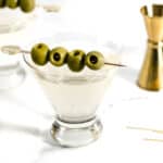 A martini glass with olives in it.