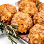 Sausage meatballs on a tray with rosemary sprigs.