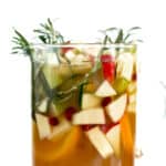 A Thanksgiving-inspired glass of Sangria, adorned with fruit and sprigs of rosemary.